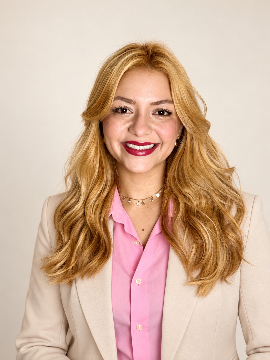 Tainá Verusca, sorrindo, com blusa rosa e blazer claro.